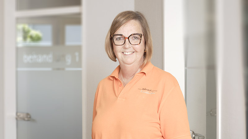 Zahnmedizinische Fachangestellte Birgit Hörsting steht vor einer Behandlungstür in der Praxis