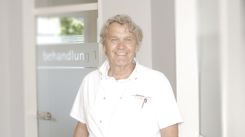 Zahntechniker Fritz Huser steht vor einer Behandlungstür in der Praxis